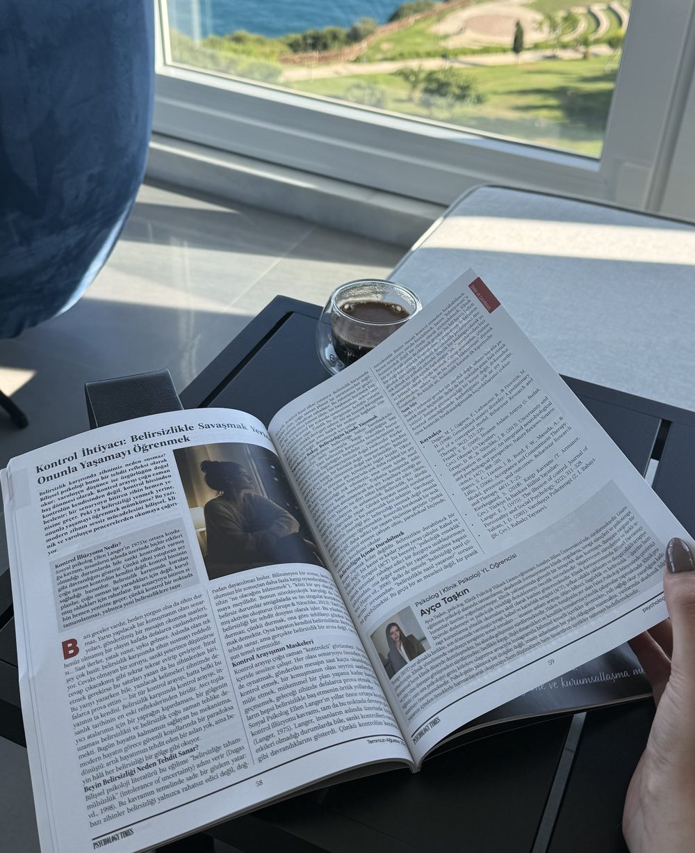 Psychology Times dergisinin basılı sayısında Ayça Taşkın'ın yazısı, deniz manzaralı bir pencerenin önünde